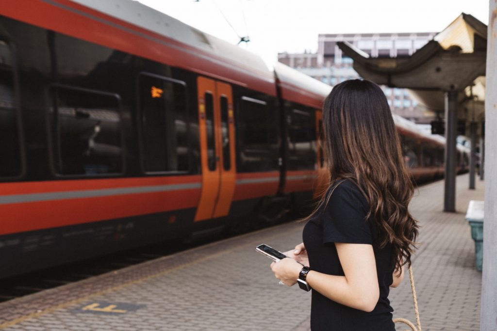 Woman using mobile at train station waiting for train