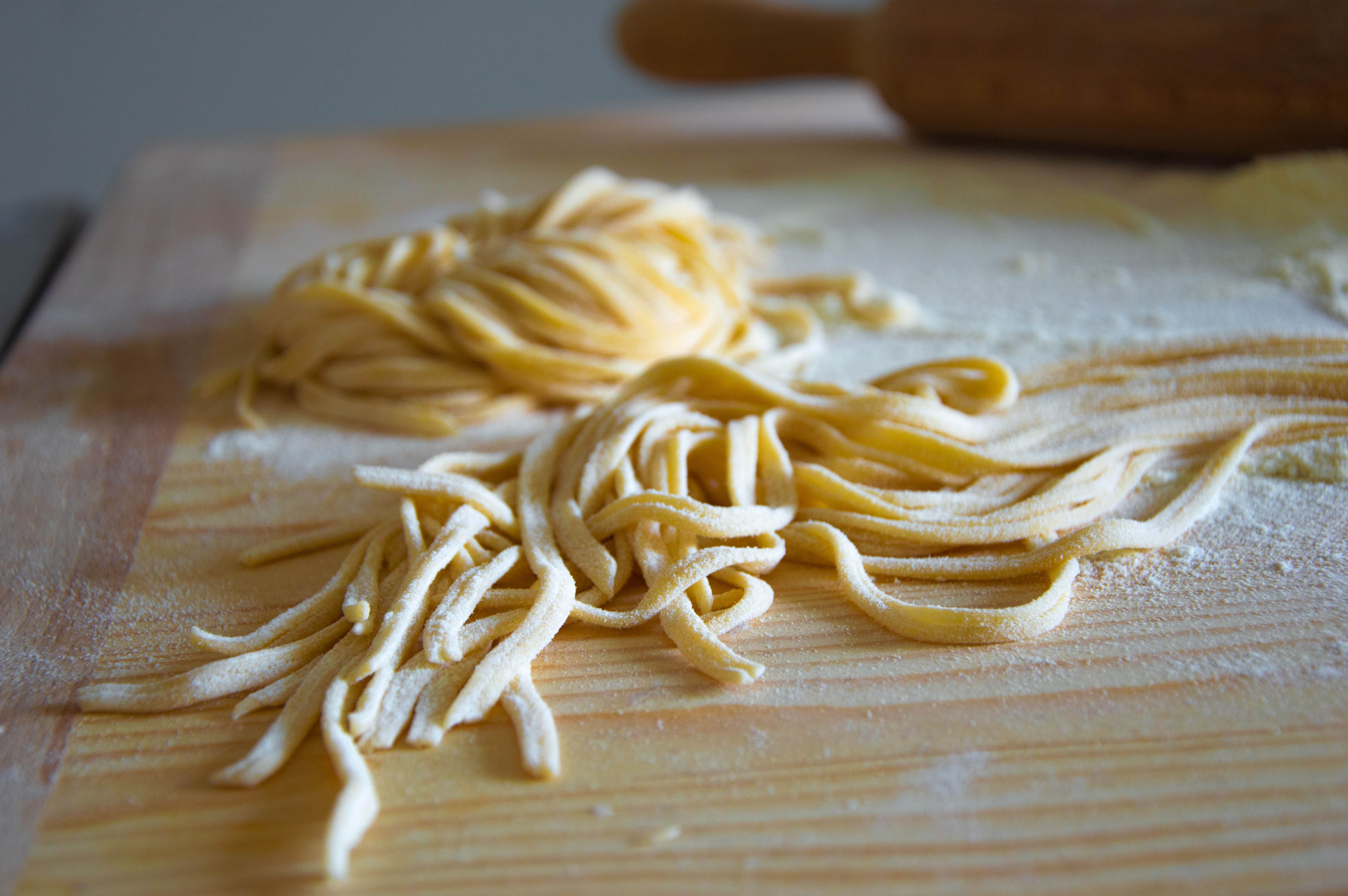 Close-up of fresh uncooked pasta on a flour-dusted wooden board, capturing authentic Italian cuisine.