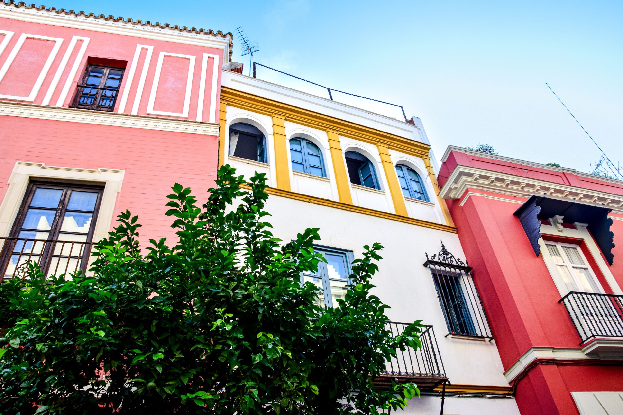 Vibrant colored facades of residential buildings in Seville, Spain, showcasing Spanish architectural style.