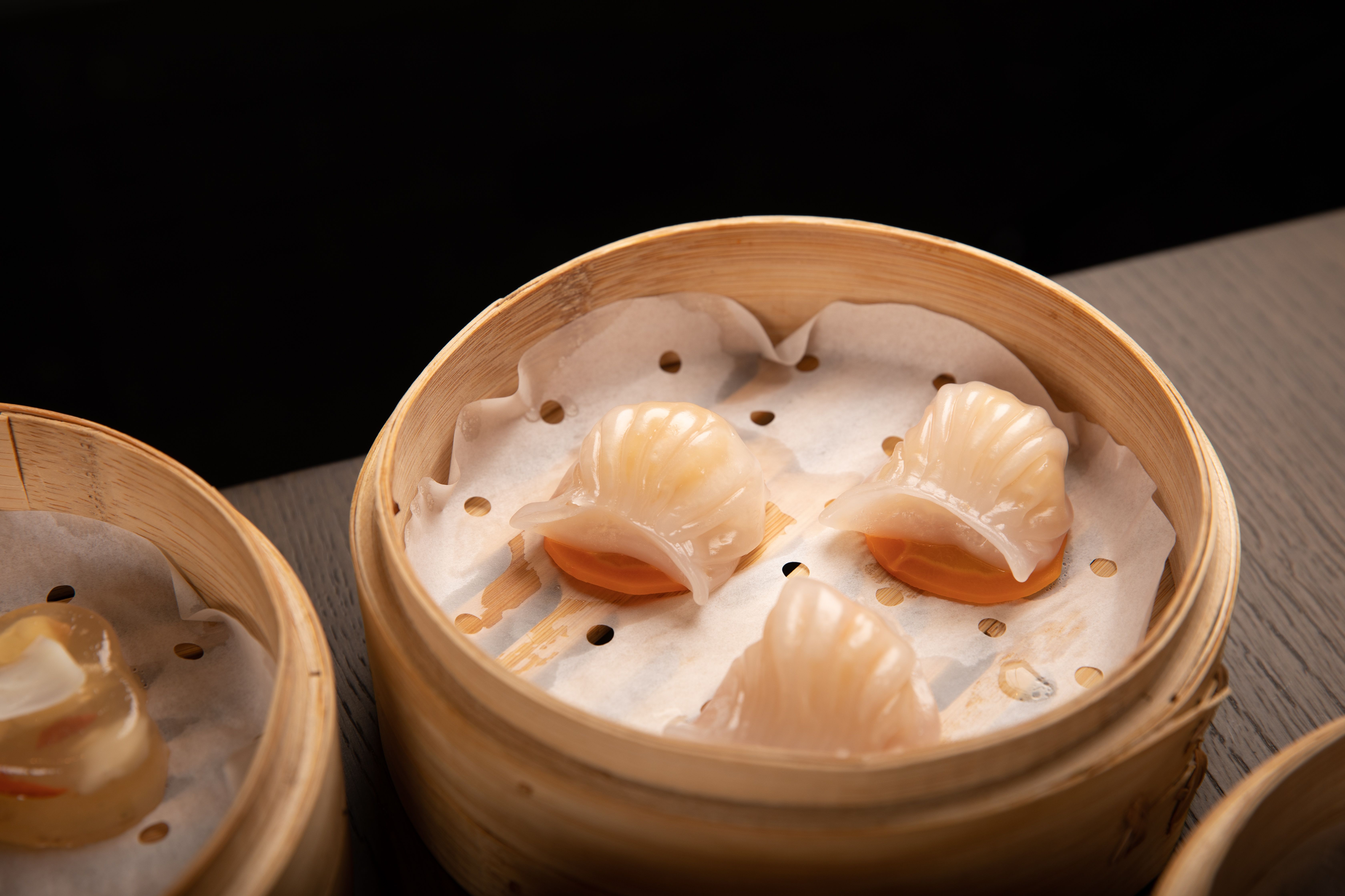 Close-up of steamed dim sum dumplings in a traditional bamboo basket, perfect for Asian cuisine themes.