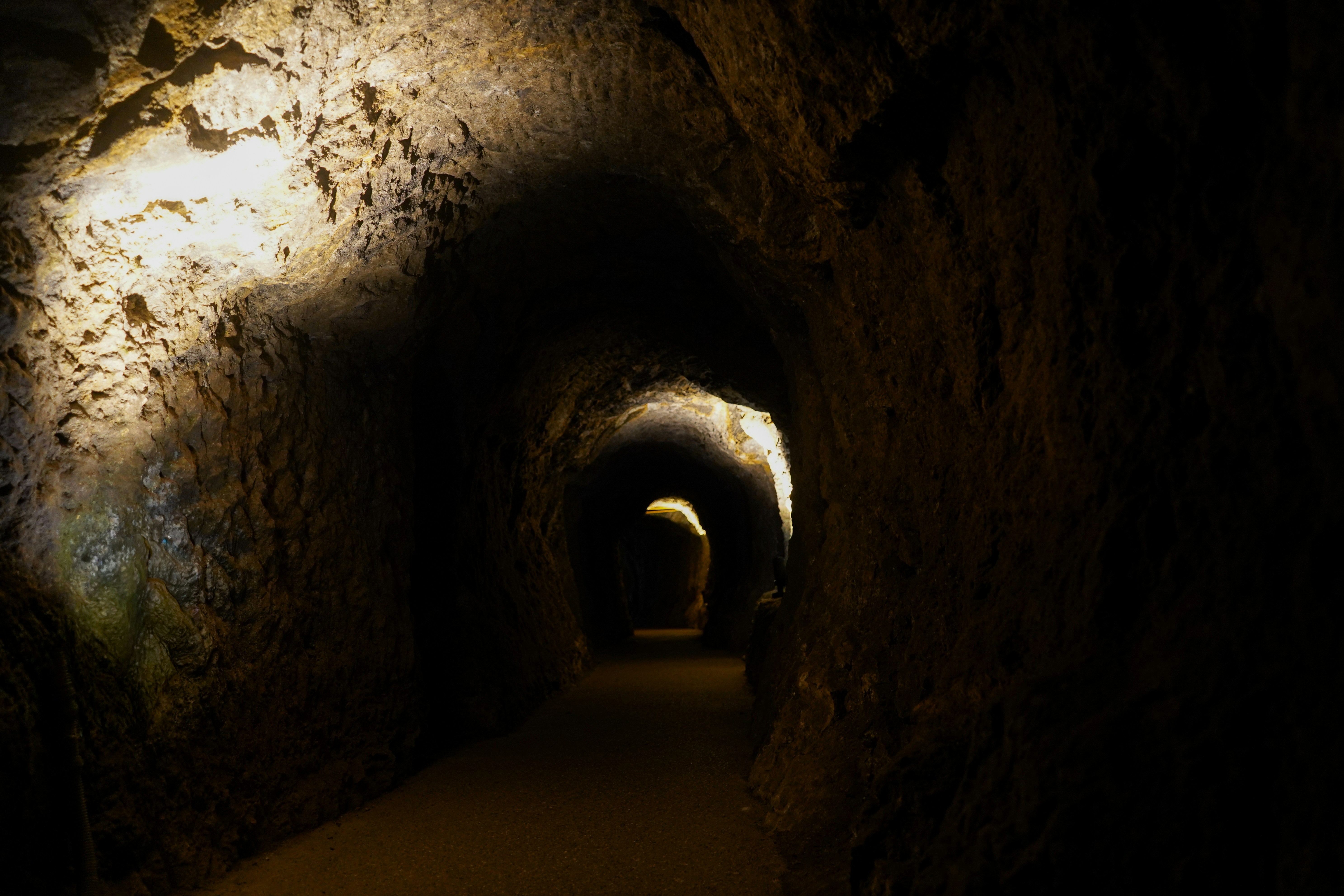A dimly lit cave tunnel with rough textured walls.